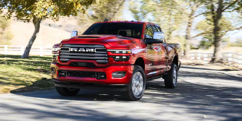 Red RAM 2500 heavy-duty pickup driving on an open road, highlighting its powerful performance, bold styling, and work-ready capability.