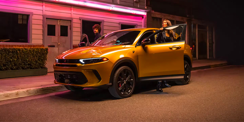 Yellow 2026 Dodge Hornet stopped on a night road as passengers step out, highlighting its sleek design, bold styling, and urban-ready presence.