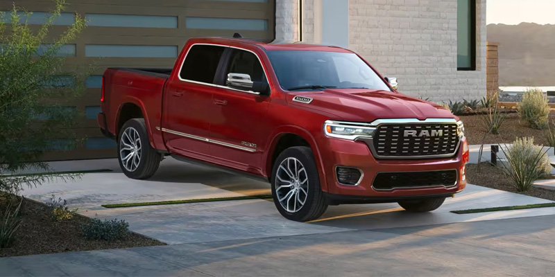 A red RAM 1500 truck parked in a driveway in front of a modern home.